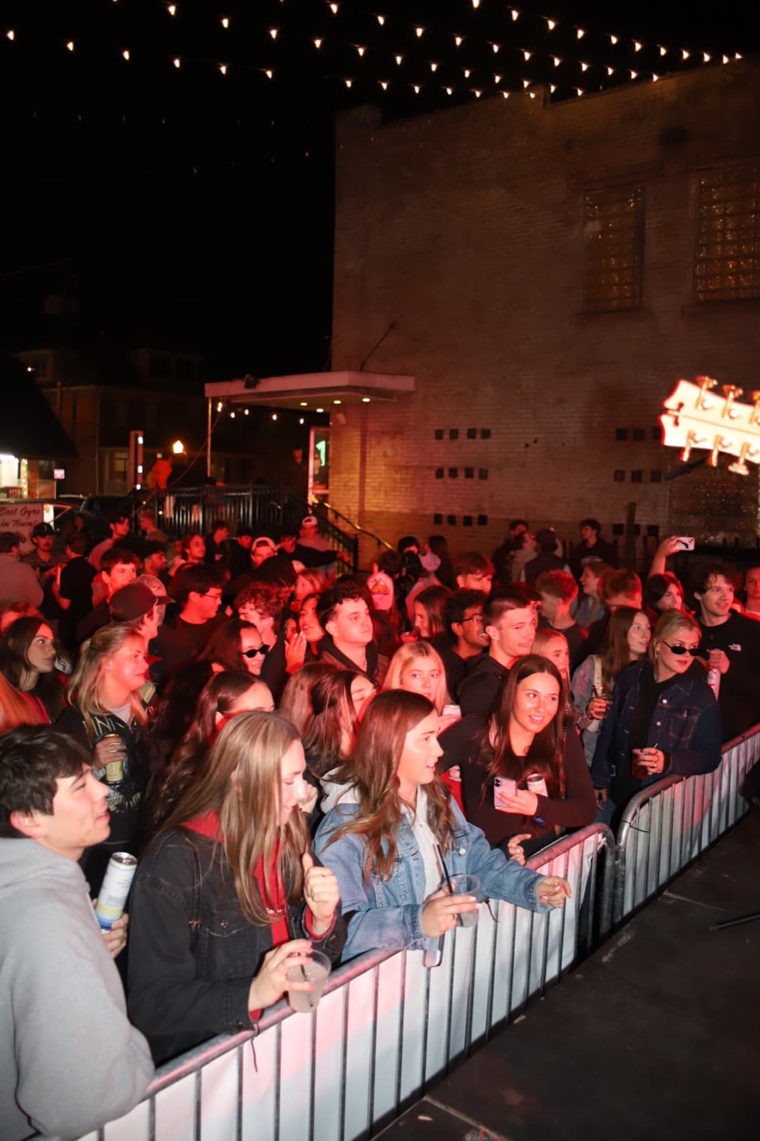 The crowd pressed against the barricade under string lights