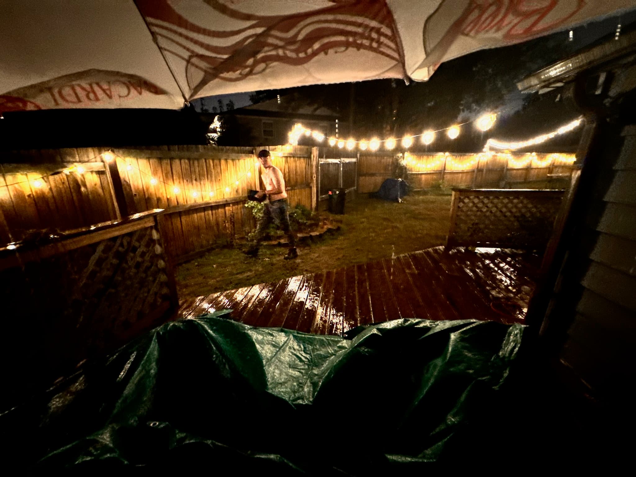 Ty in the rain-soaked backyard at Elliot Ave, string lights overhead